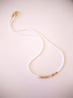 There is something different about this necklace. First of all, there are not too many left. Second, it has THE perfect amount of sparkle, that sparkle that comes to life when you move, converse, dance, or while you are having a romantic dinner. This necklace is made with white seed beads and gold Swarovski accent stones. It is as minimalist and delicate as it gets! Choose size 14" at checkout for choker style, or choose the length that suits you best! Also available with other accent color ston Dainty White Choker With Delicate Chain, Delicate White Choker Jewelry, White Bohemian Choker With Colorful Beads, Delicate White Choker Necklace, Adjustable Gold Bead Choker Necklace, Adjustable Choker Necklace With Gold Beads, Adjustable Gold Beads Choker Necklace, White Beaded Chain Necklace For Festival, Colorful Beaded White Jewelry For Festivals