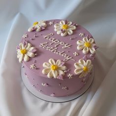 a pink cake with white and yellow flowers on it