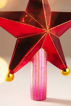 a red and gold star on top of a pink vase