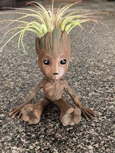 a small groote sitting on top of a granite floor next to a planter