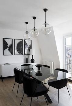 a dining room table with black chairs and art on the wall