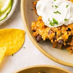 two bowls filled with mexican food next to tortilla chips