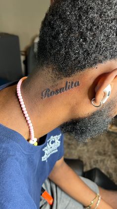 a woman with a name tattoo on her left side behind her ear is sitting in front of a laptop