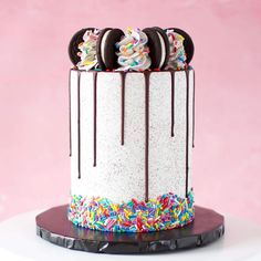 a white cake with sprinkles and oreo cookies sitting on top of it