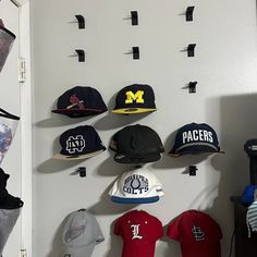 several hats are hanging on the wall in front of a baseball bat and glove rack