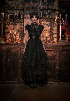 a woman standing in front of a bar with candles on the wall and an antique cabinet behind her