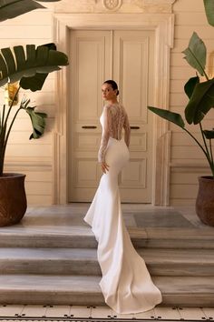 a woman is standing on some steps wearing a dress with long sleeves and an open back