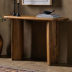 a wooden table sitting in front of a wall with a vase on top of it