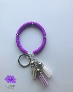 a purple bracelet with three tassels hanging from it's end and a keychain attached to it