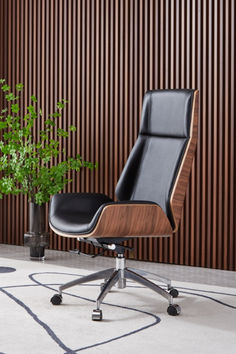 an office chair next to a potted plant in front of a wooden paneled wall