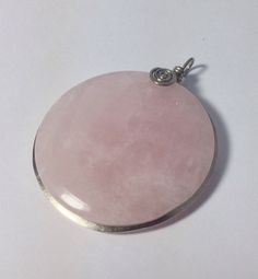 Large round rose quartz pendant set in nickel silver wire and decorated with a small spiral. Diameter 47mm An adjustable length leather strap is included. "In esotericism, rose quartz is considered a strong symbol of love and fertility. It is said to heal physical and mental weaknesses in love life, as well as to relieve headaches, for example, which is why it is considered a healing stone. It also belongs to the heart chakra and is said to heal the organs Strengthen the heart area. Furthermore, Pink Jewelry For Meditation, Rose Quartz Jewelry For Meditation, Round Rose Quartz Jewelry For Meditation, Silver Rose Quartz Jewelry For Meditation, Wire Wrapped Rose Quartz Round Jewelry, Pink Rose Quartz Round Pendant Jewelry, Strong Symbol, Rose Quartz Pendant, Nickel Silver