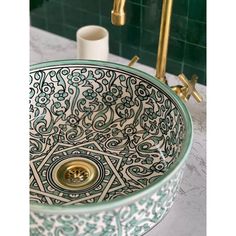 a green and white bowl sink sitting on top of a counter next to a faucet