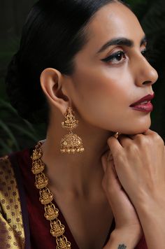 This opulent intricacy worked in geru gold plated silver alloy has its charm in its regal detailing. The monotonicity of gold is eased by adding the pretty pearls accentuating the charm of this temple work beauty. Necklace Closure - Adjustable Dori Earrings Closure - Push Back Style Tip - Style this with classic banarasi sarees, lehengas or indo western wear dresses. A perfect match with almost any traditional classic. This one comes straight off a nani inspired jewelery wardrobe and offers hint Gold Plated Yellow Gold Kundan Necklace For Puja, 22k Gold Tilla Jewelry For Puja, Elegant Heavy Brass Temple Necklace, Yellow Gold Meenakari Jewelry For Puja, Yellow Gold Chandbali Temple Necklace For Puja, Gold Brass Jhumkas For Wedding, Yellow Gold Brass Jhumkas For Wedding, Yellow Gold Filigree Jewelry For Puja, 22k Gold Jewelry For Puja