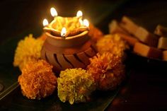 a lit candle sitting on top of a table next to some flowers and candles in front of it