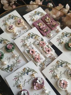 several cards with flowers and pearls on them are sitting on a table next to each other