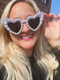 a blonde woman wearing heart shaped sunglasses on top of her head and looking at the camera