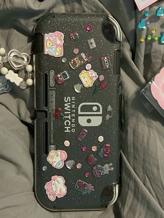 an iphone case with stickers on it laying on a bed next to other items