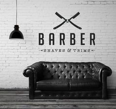 a black and white photo of a leather couch in front of a brick wall that says barber shaves & trims