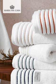 a stack of white towels sitting on top of a wooden table next to a plant