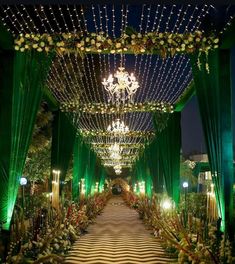 an elaborately decorated walkway is lit up with green lights and greenery at night