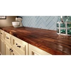 a wooden counter top in a kitchen with white cabinets