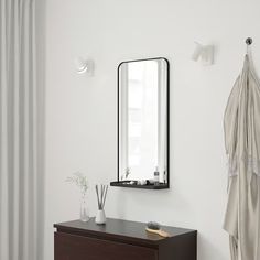 a white room with a mirror, vase and other items on the dresser next to it