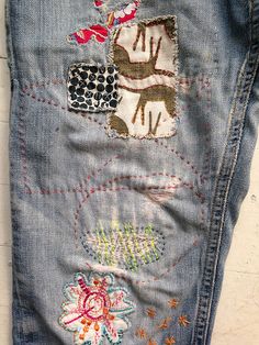 an old pair of jeans with embroidered patches on them