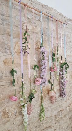 flowers hanging from the side of a stone wall with ribbons attached to it's sides