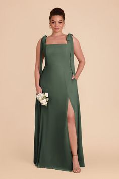 a woman in a long green dress with one leg slited and flowers on the side