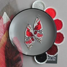 red and white beaded earrings sitting on top of a plate next to other beads