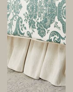 an upholstered headboard with blue and white floral wallpaper on the back