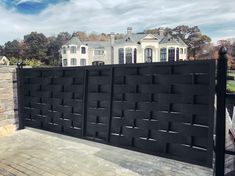 a large black fence is in front of a house with a stone wall and brick walkway