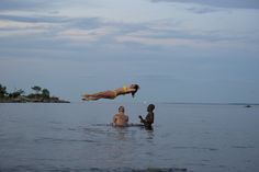 two people are in the water and one person is jumping into the air above them