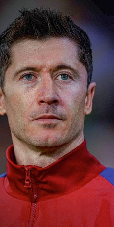 a man in a red and blue jacket looking at the camera with a serious look on his face