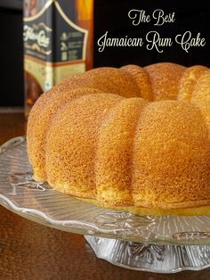 a bundt cake sitting on top of a glass platter next to a bottle