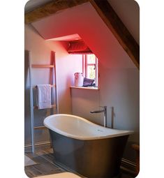 an old fashioned bathtub in the corner of a bathroom with red light coming from it's window