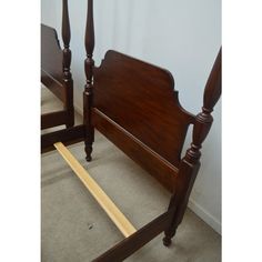 a wooden bed frame sitting on top of a carpeted floor next to a wall