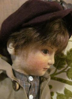 a close up of a doll with a hat on it's head and hair