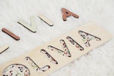 the wooden name sign is made out of wood and has floral designs on it, along with other letters