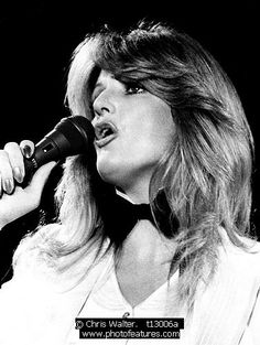 a black and white photo of a woman singing into a microphone