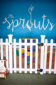 a white picket fence in front of a blue wall with the words sprouts painted on it