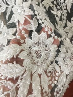 closeup of white lace on fabric with flowers and leaves in the center, as seen from above