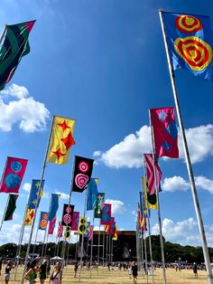 many colorful flags are flying in the air on a sunny day with blue skies and white clouds