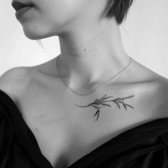 a woman wearing a black dress has a small branch tattoo on her chest and neck