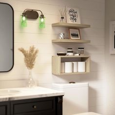 a white toilet sitting next to a bathroom sink under a mirror and shelf above it