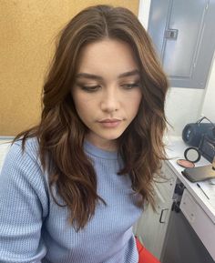 a woman with long brown hair sitting in front of a mirror