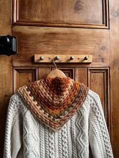 a sweater hanging on a coat rack in front of a wooden door