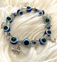 The Evil Eye Bracelet, Evil Eye Charm Bracelet, Blue Charm Bracelet, Handmade Blue Stretch Bracelet For Festivals, Adjustable Charms Bracelets For Festival, Adjustable Blue Symbolic Bracelet, Blue Round Spiritual Charm Bracelet, Blue Evil Eye Dangle Jewelry, Blue Dangle Bracelets With Charms