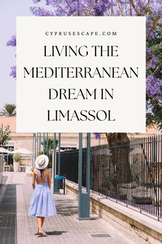 a woman in a blue dress and hat walking down the street with a white sign that says living the mediterranean dream in limasol