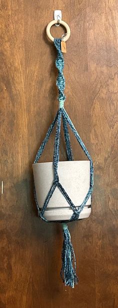 a hanging planter made out of paper and rope on a wooden surface with a hook